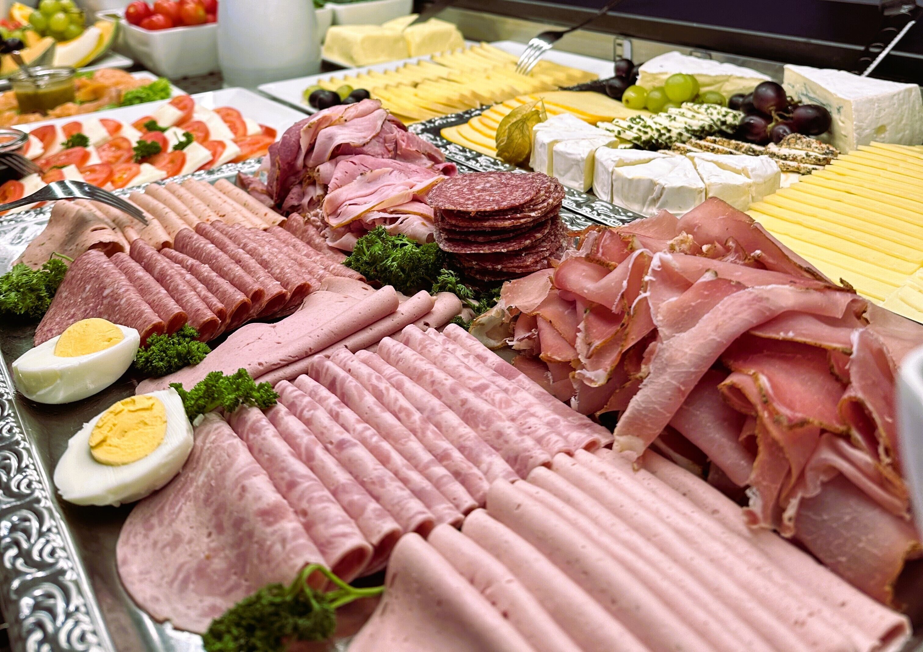Eine Auswahl an Käse, Fleisch und Obst auf einer Platte.