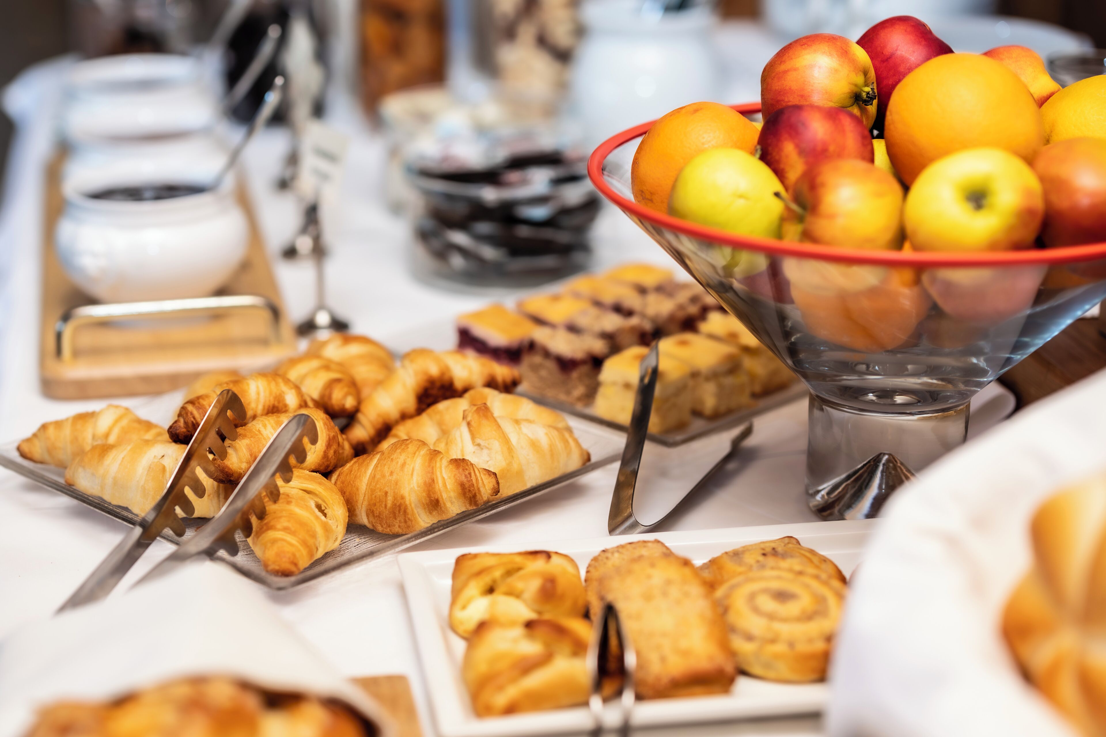 Un bufé con diversas opciones de pastelería, frutas y bebidas.