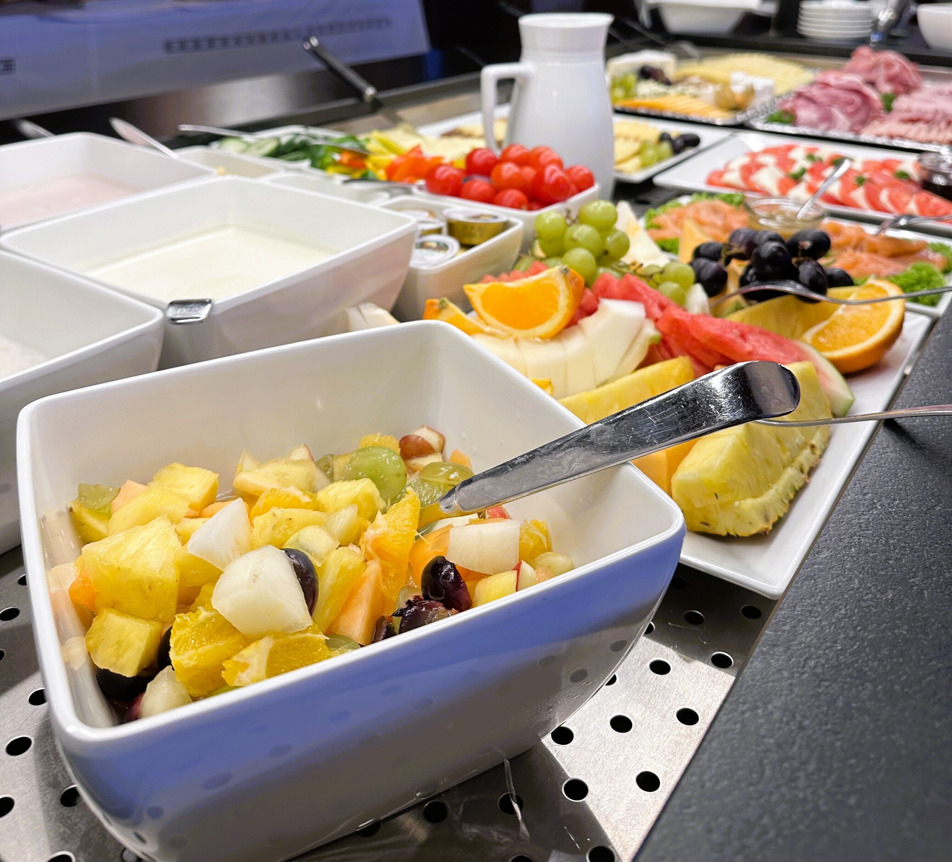 Un bufé con diversas opciones de comida, como frutas, verduras y carnes.