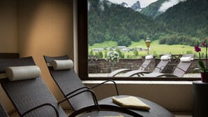 A room with reclining chairs and a large window offering a view of a mountainous landscape. - Hotel Elisabeth (Schoppernau)