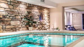 A pool area with a stone wall and a potted plant. - Hotel Elisabeth (Schoppernau)