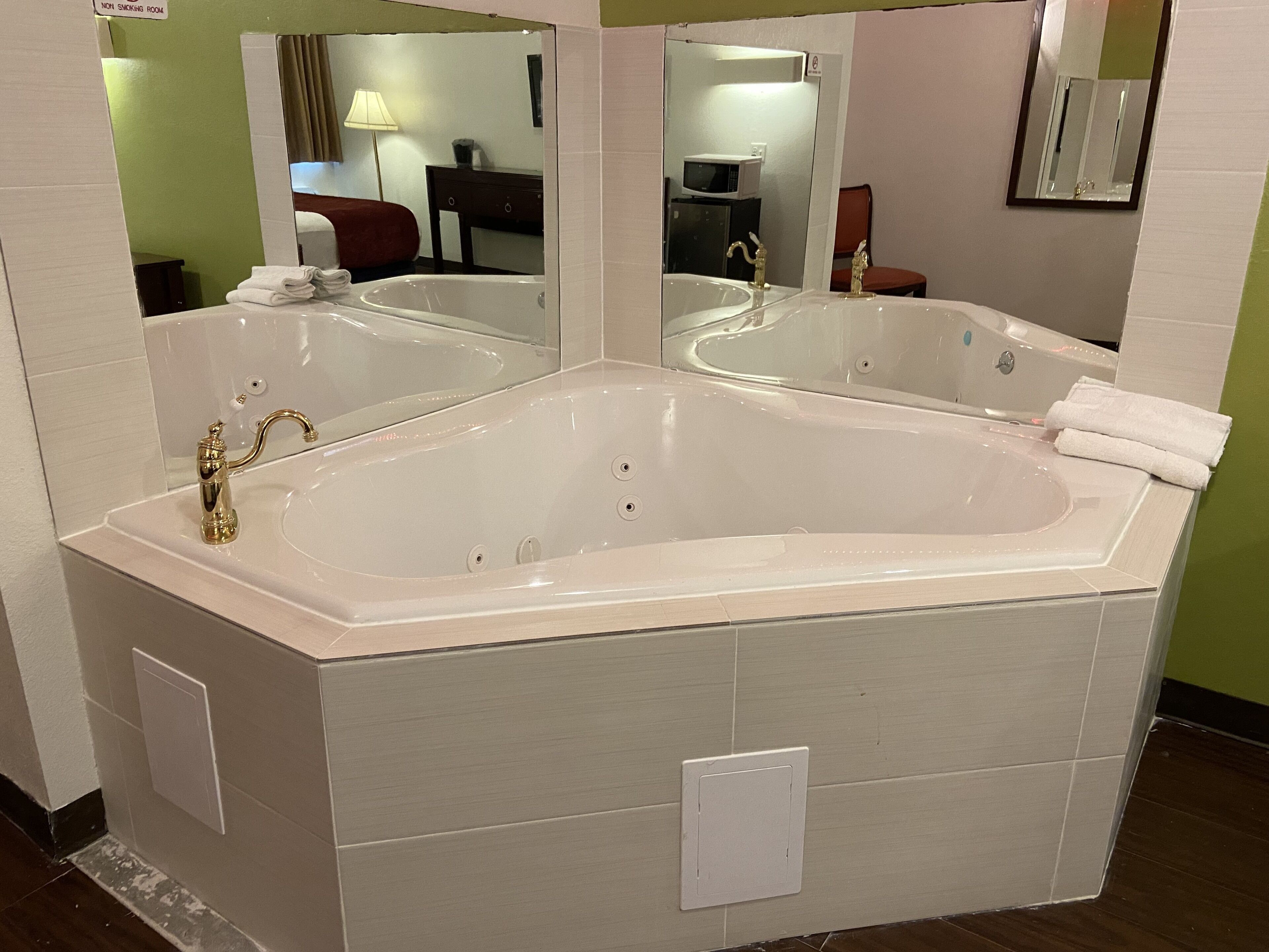 Une grande baignoire sur pieds, placée dans une salle de bain avec un miroir au-dessus.