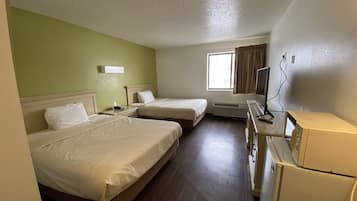 Habitación de hotel con dos camas, un escritorio, un refrigerador y una ventana con cortinas.
