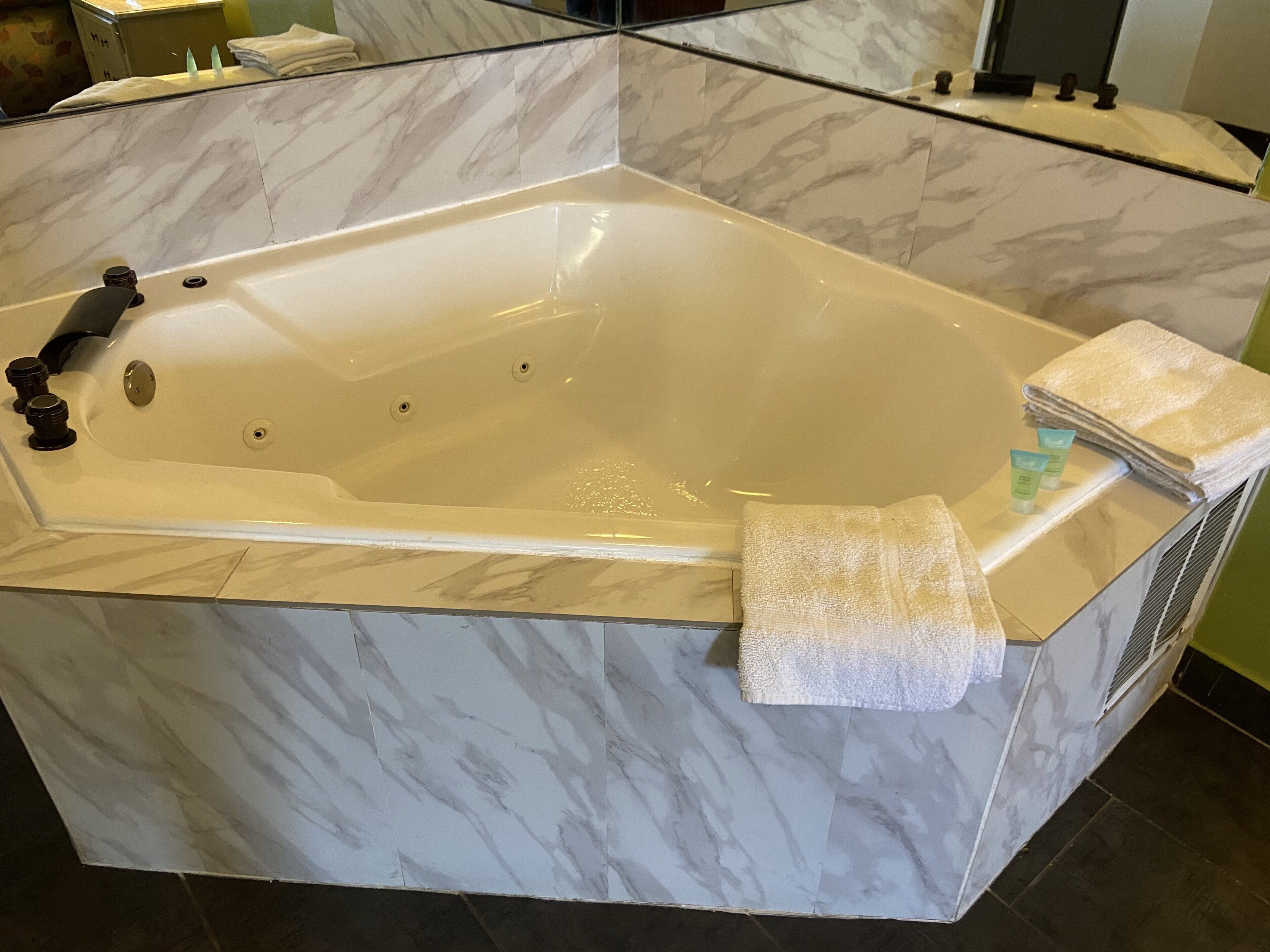 A large, freestanding bathtub with a marble finish, a towel, and a bottle of lotion on the side.