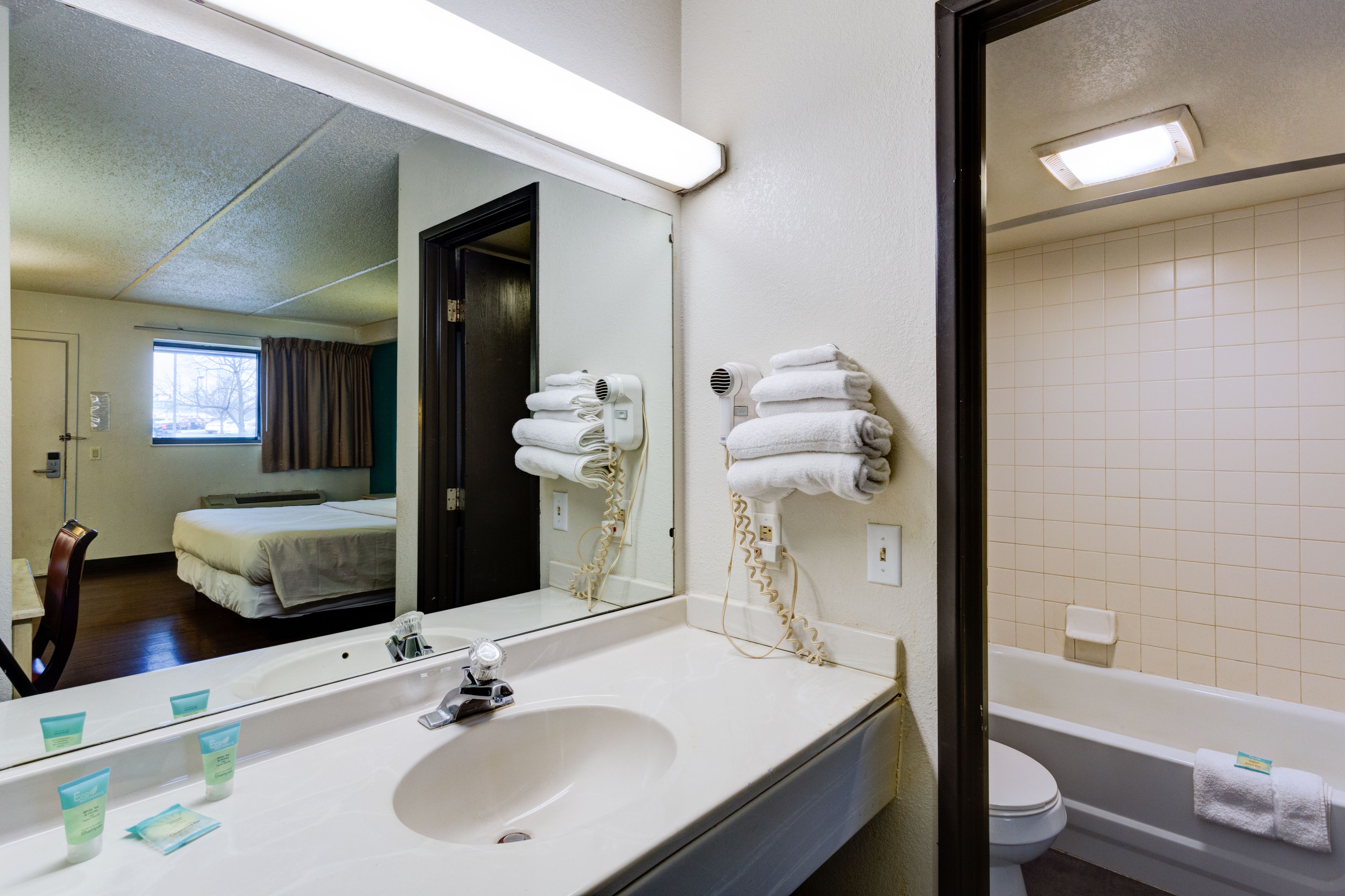 Un baño de hotel con un espejo grande, un lavabo, un inodoro y una bañera.