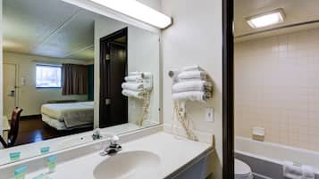 Un baño de hotel con un espejo grande, un lavabo, un inodoro y una bañera.