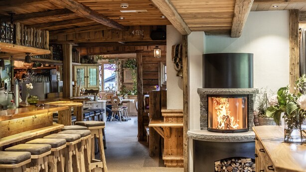 Un intérieur rustique avec une cheminée en pierre, un bar en bois et un coin salon confortable.