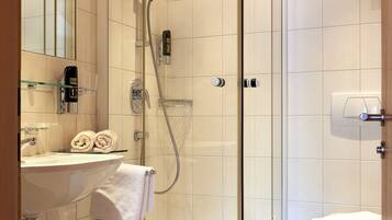Ein modernes Badezimmer mit einer begehbaren Glasdusche, einer Badewanne, einem Waschbecken mit Glasablage und einer Toilette.