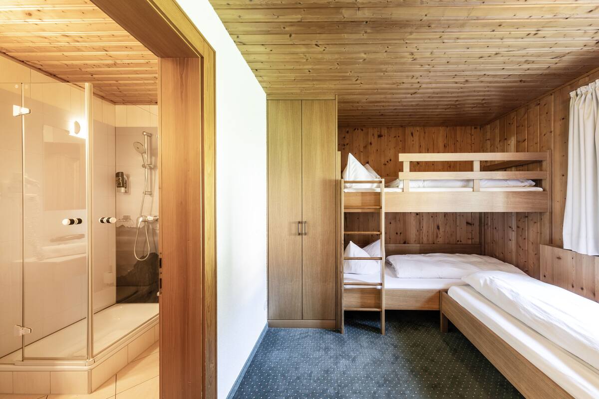 Una habitación de cabaña de madera con literas, una zona de ducha y un armario.