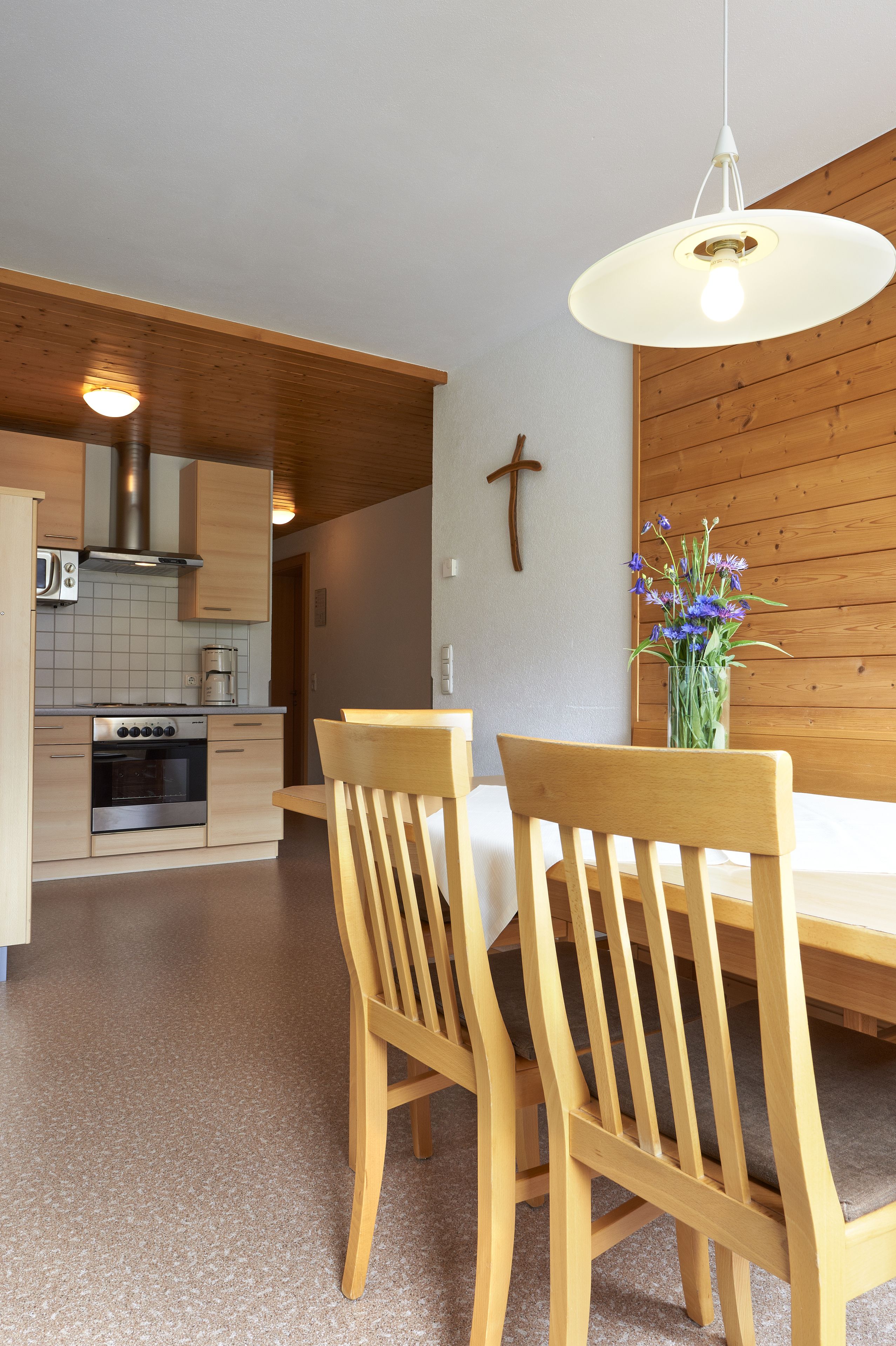 Eine moderne Küche mit Holzausstattung, einem Edelstahlbackofen und einer Pendelleuchte.