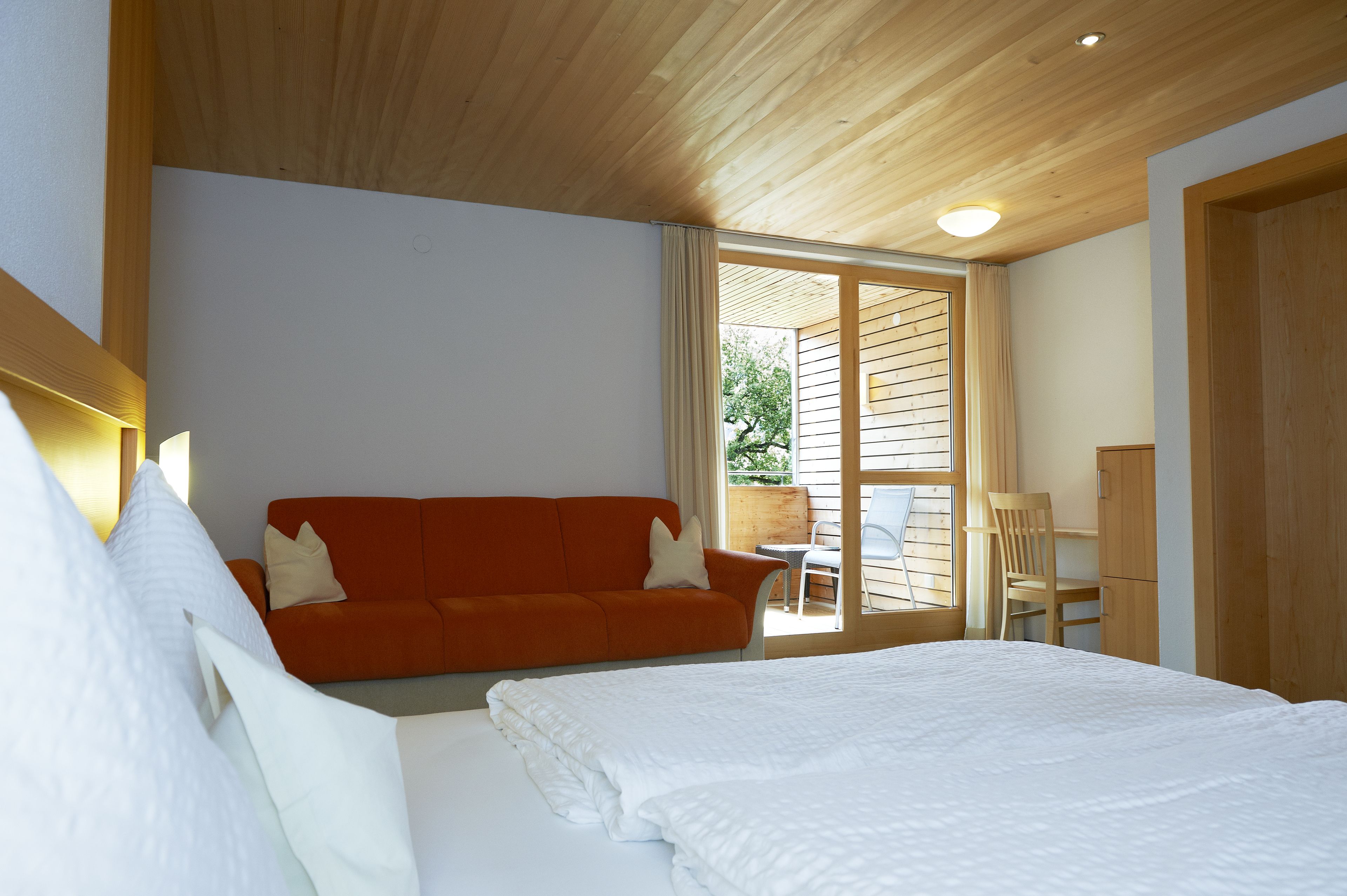 Un dormitorio con cama, sofá, sillón y escritorio.