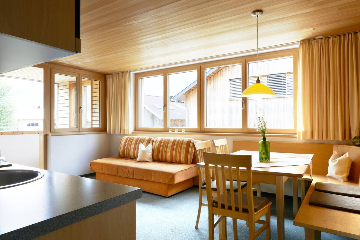 Una cocina moderna con encimera de madera, horno empotrado y ventana con cortinas.