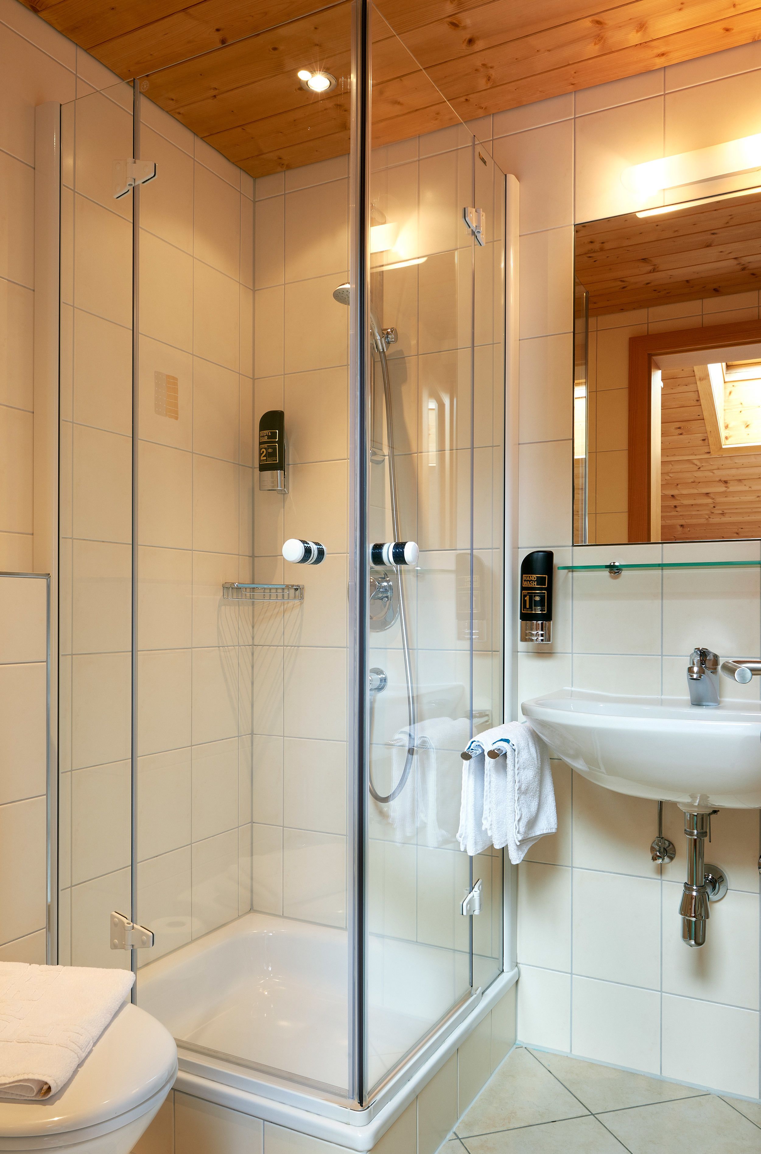 Un bagno moderno con doccia vetrata, lavabo bianco e water.