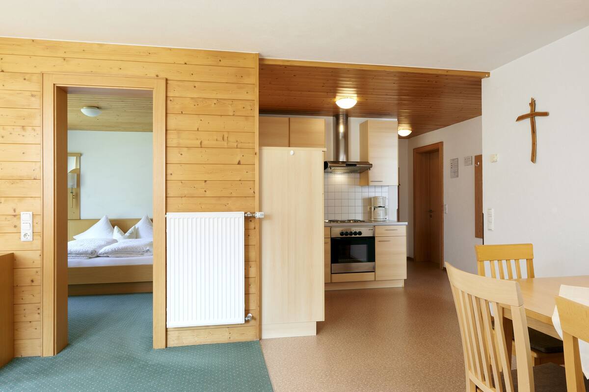 Un interior de madera con cama, mesa de comedor y zona de cocina.
