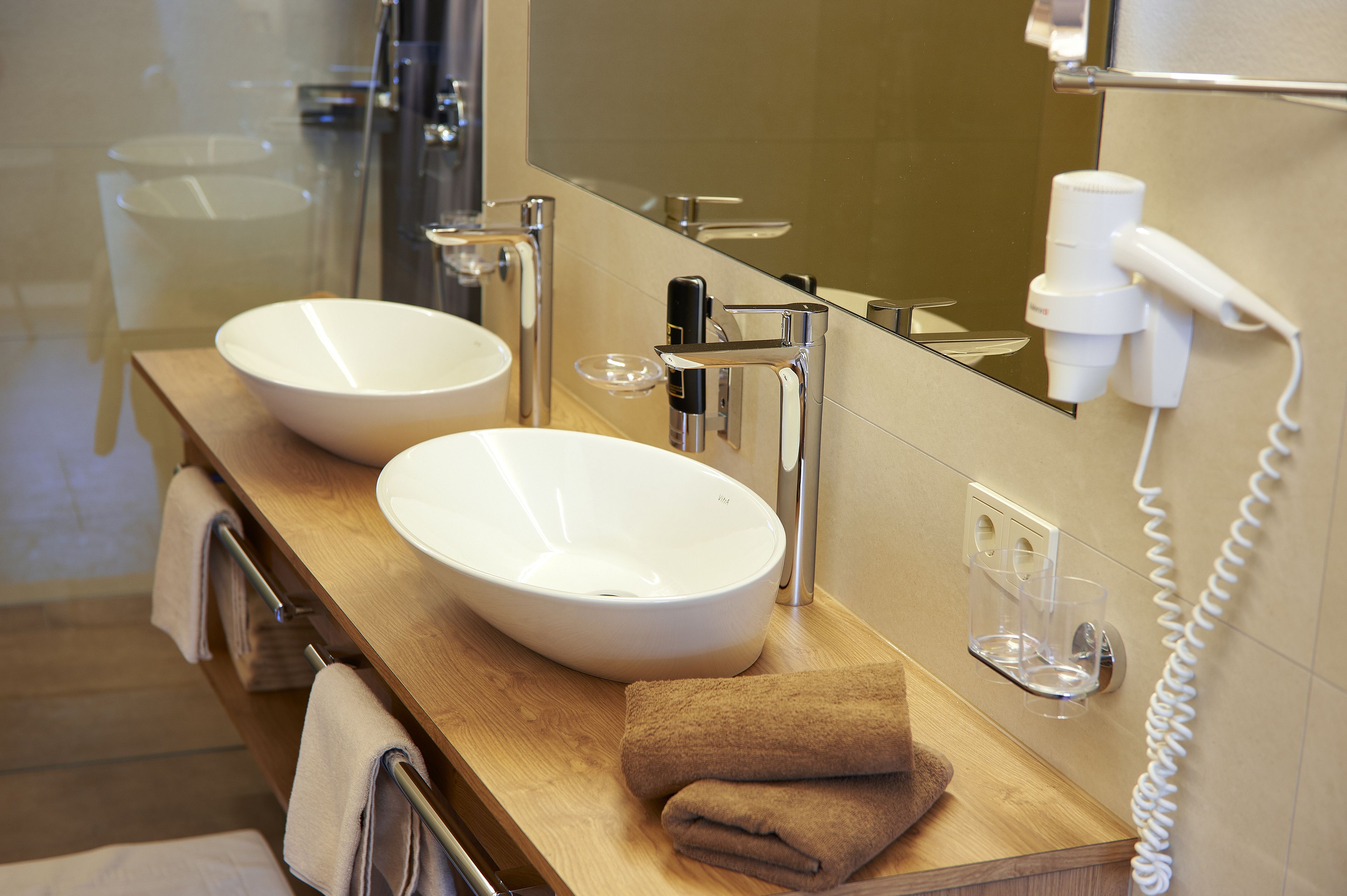 Un bagno con due lavandini, uno specchio, un portascopino e un asciugacapelli.
