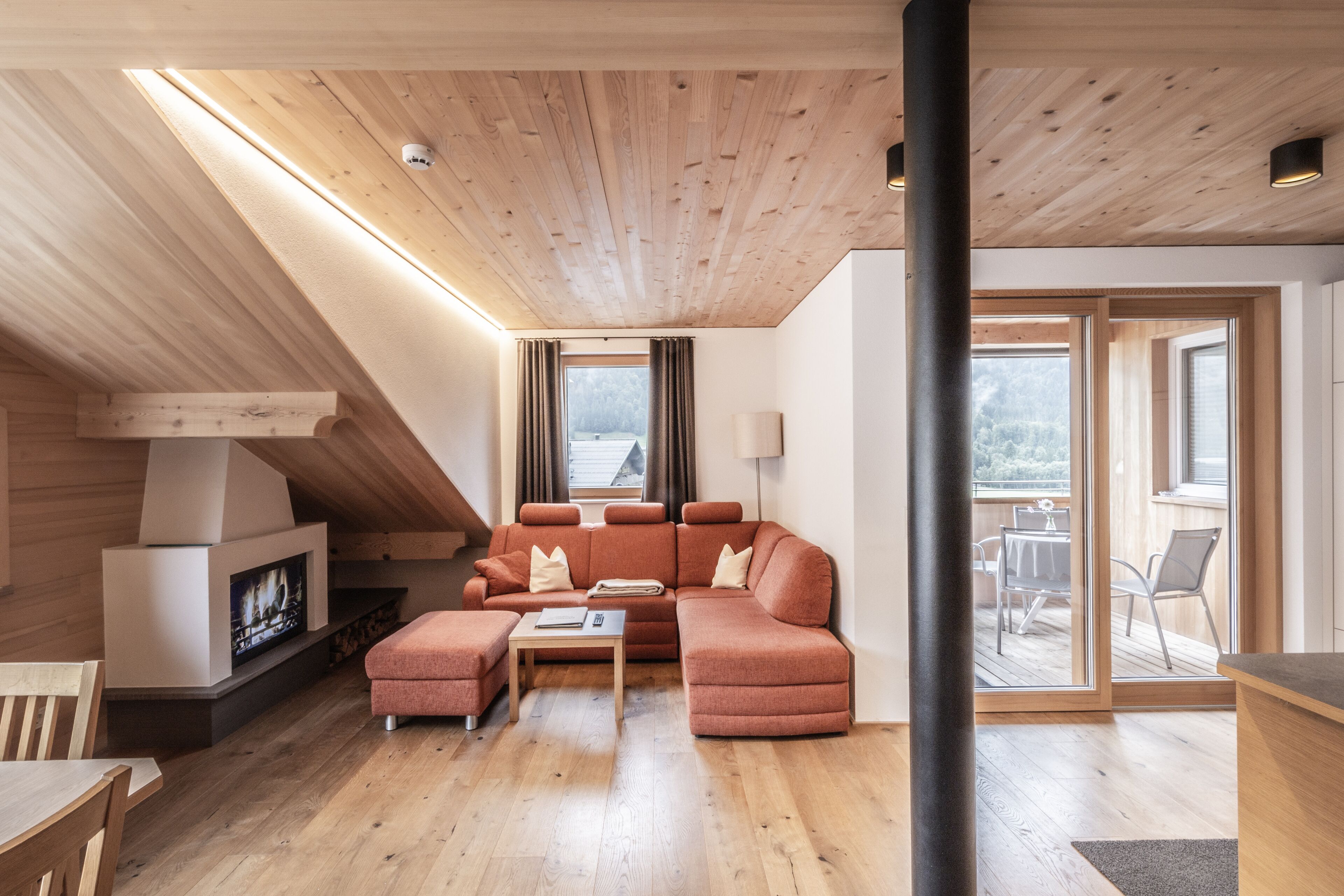 Ein modernes Wohnzimmer mit Holzboden, Kamin, einer Couch und einem Essbereich.