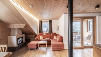 Ein modernes Wohnzimmer mit Holzboden, Kamin, einer Couch und einem Essbereich.