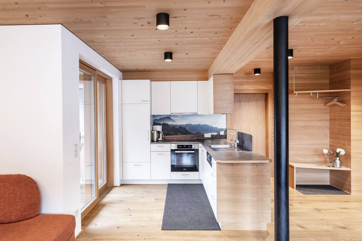 Una cocina moderna con armarios de madera, horno empotrado y un amplio ventanal con vistas a un paisaje pintoresco.