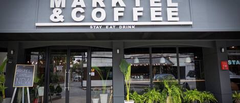 A storefront with a sign reading "MARKTEL & COFFEE" and a slogan "STAY EAT DRINK".