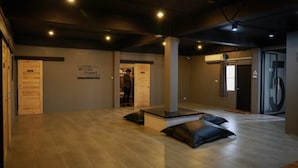 A spacious room with a wooden floor, a large pillar, and a door with a sign. - Marktel&Coffee - Hostel (Chiang Mai)