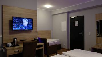 Habitación de hotel con televisión, escritorio, dos camas y puerta.