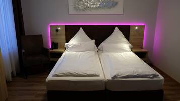 Ein Doppelbett mit weißer Bettwäsche, ein Nachttisch mit Lampe und ein Wandbild über dem Bett.