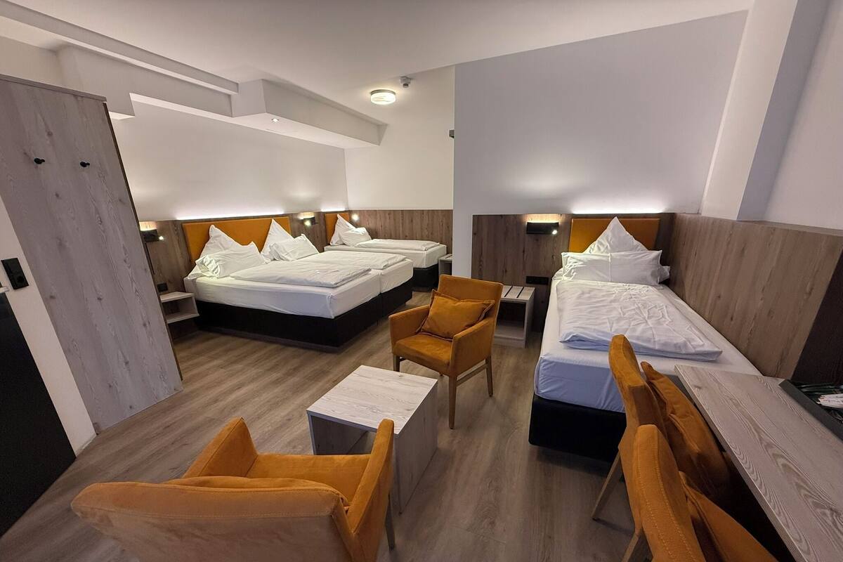 Habitación de hotel con dos camas, un escritorio, una silla y una mesita.