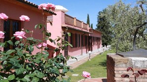 Un bâtiment rose doté d’un jardin et d’une pergola.