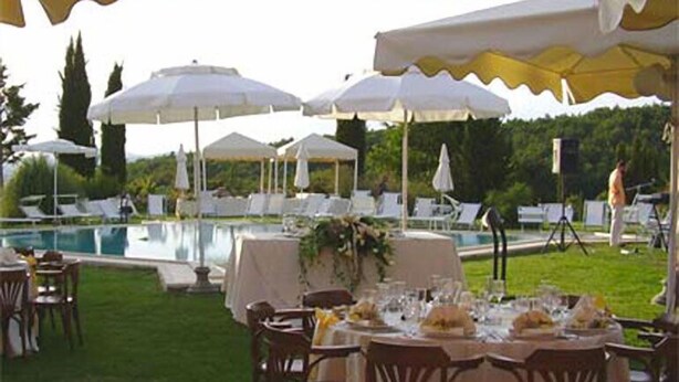 Un espace de restauration en plein air, avec des tables dressées pour le repas, entouré de parasols blancs et de chaises.