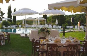 Un espace de restauration en plein air, avec des tables dressées pour le repas, entouré de parasols blancs et de chaises.
