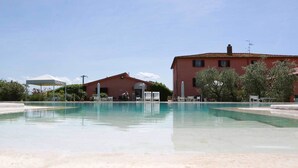 Une piscine avec des chaises longues et un bâtiment en arrière-plan.