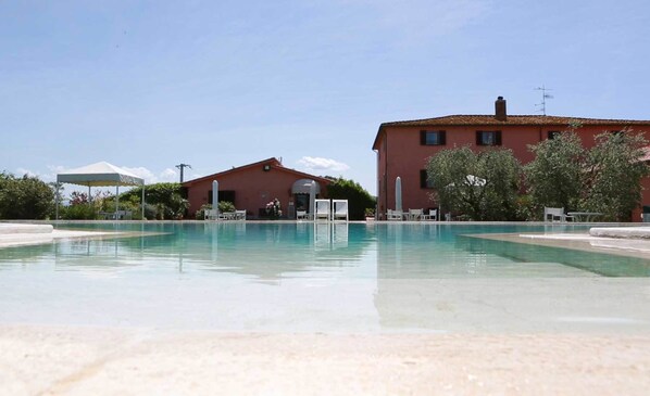 Une piscine avec des chaises longues et un bâtiment en arrière-plan.