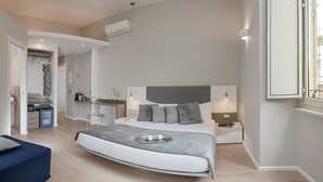 A modern bedroom with a large bed, bedside tables, a seating area, and a bathroom visible through an open door. - Colosseum Corner (Rome)