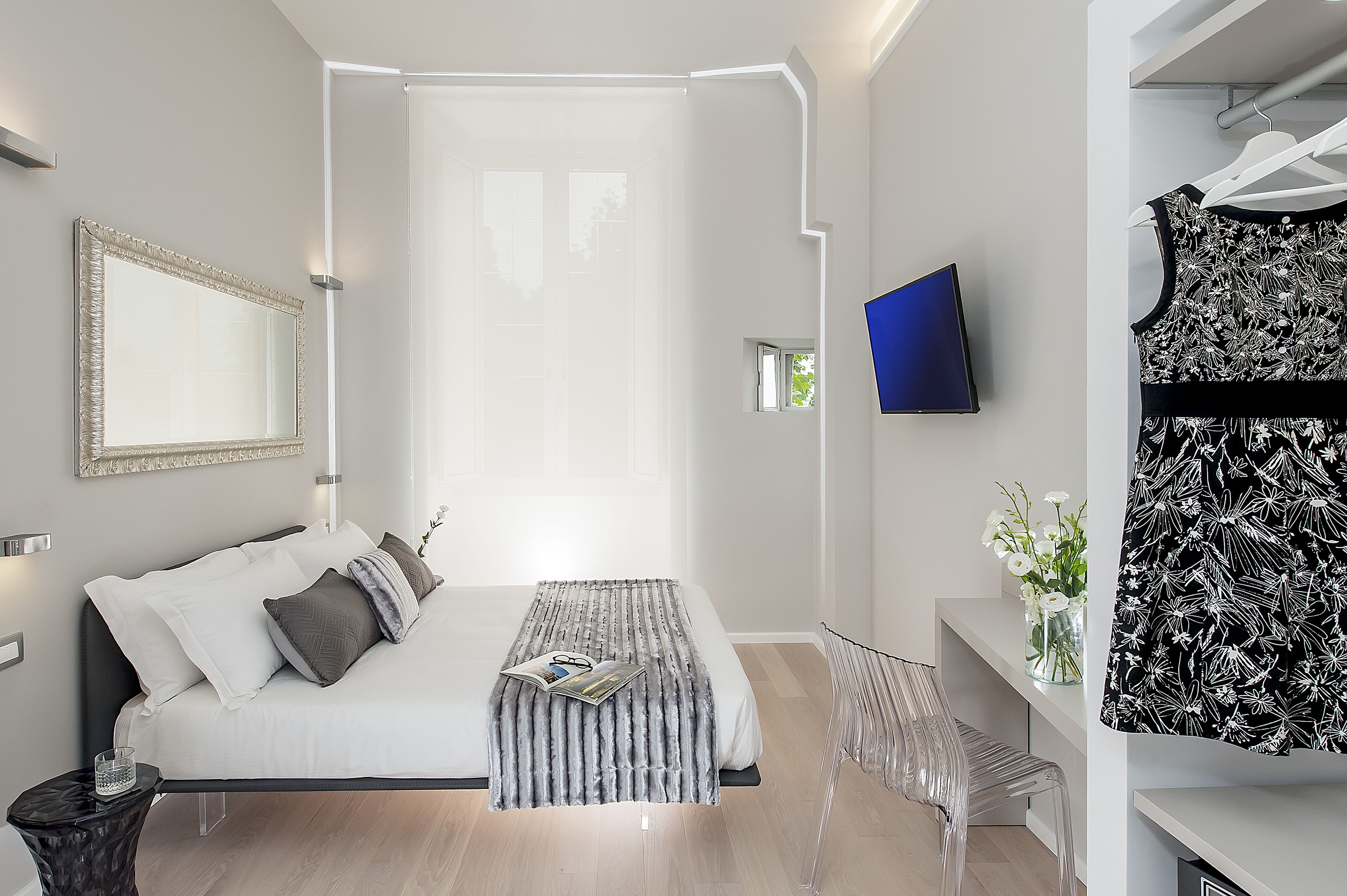 Une chambre à coucher moderne avec un lit, une table de chevet et un téléviseur fixé au mur.