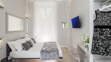 Une chambre à coucher moderne avec un lit, une table de chevet et un téléviseur fixé au mur.