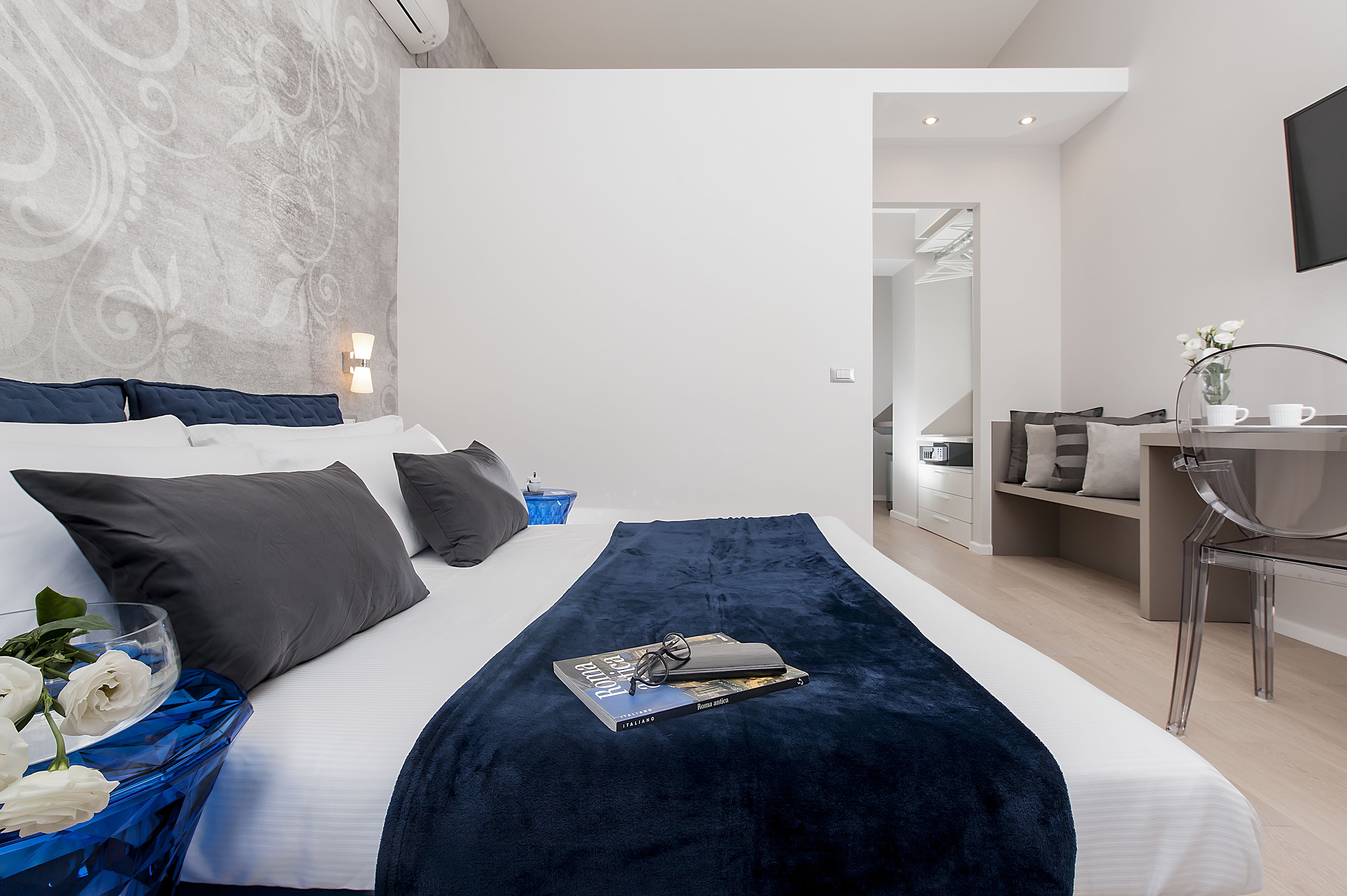 A modern hotel room with a large bed, a desk, and a mirror.
