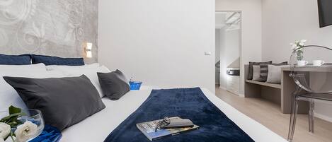 A modern hotel room with a large bed, a desk, and a mirror.