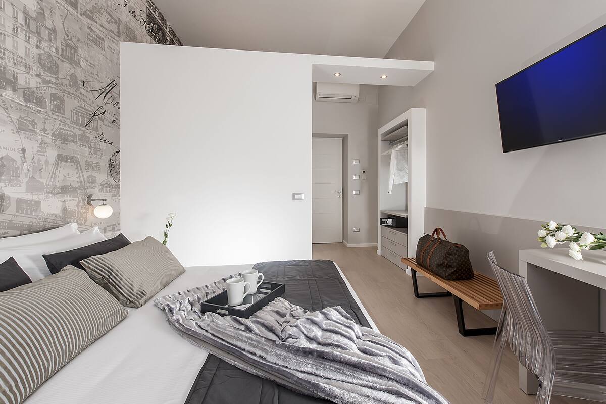 A modern hotel room with a bed, bedside table, and a TV.