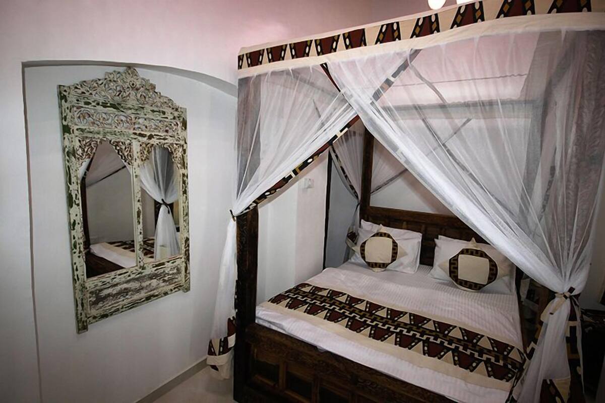 A bed with a canopy and a mirror with a decorative frame.