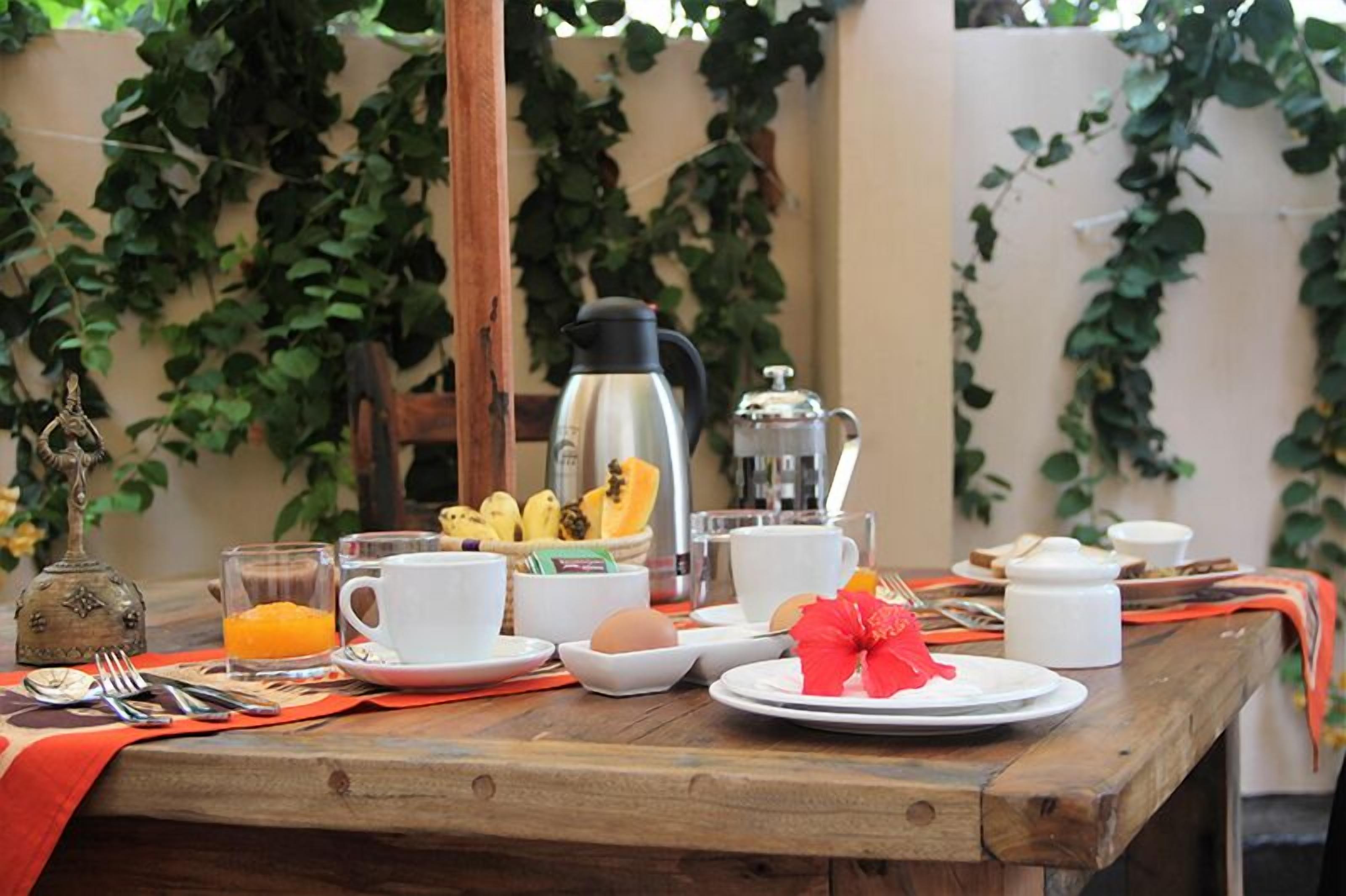 A breakfast table with coffee, tea, fruit, and eggs.