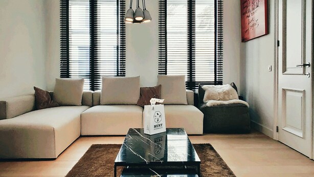 A modern living room with a sectional sofa, a glass coffee table, and a hanging light fixture. - B&B Les Invités (Bruges)