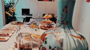 A dining table set with various dishes and a large floral vase. - B&B Les Invités (Bruges)
