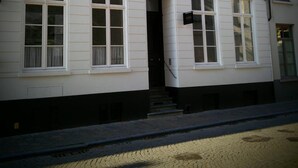 A two-story building with white siding and multiple windows. - B&B Les Invités (Bruges)