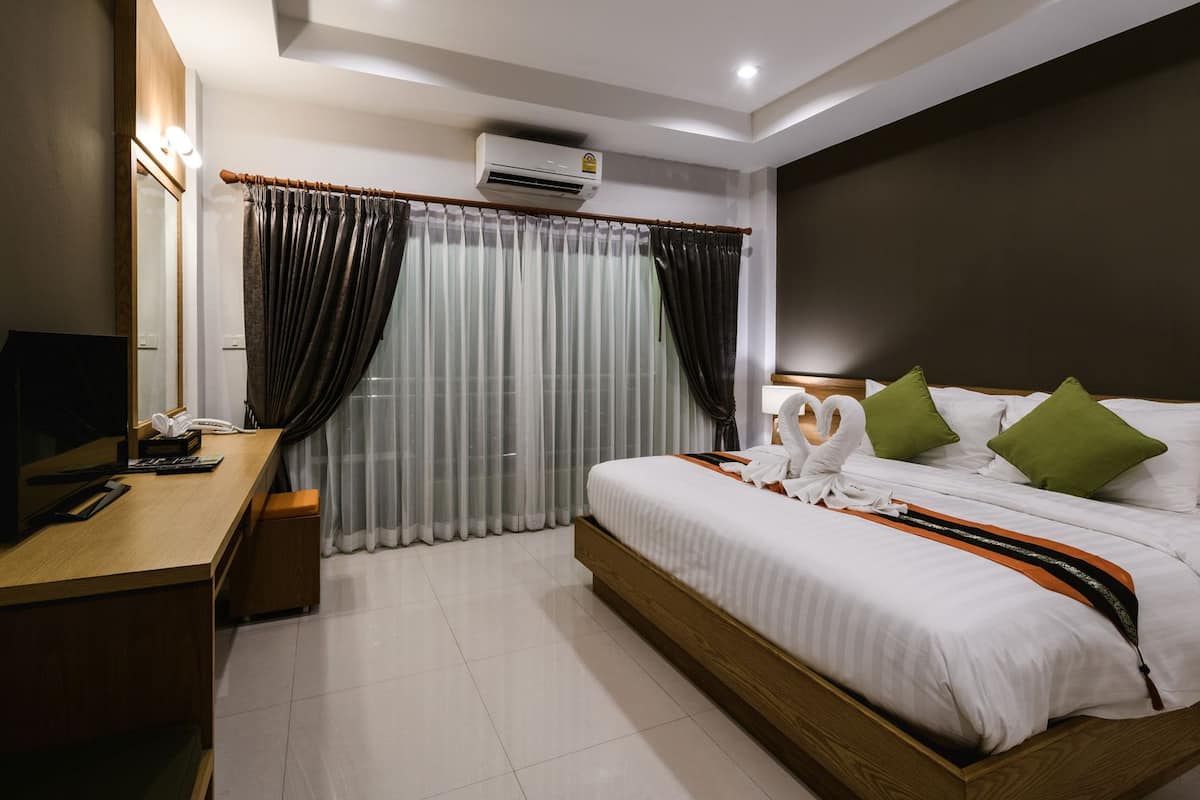 Een hotelkamer met een bed, een bureau met telefoon en een airconditioning.