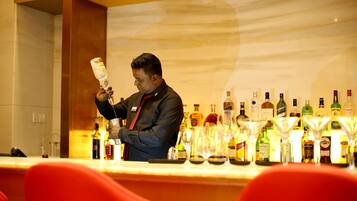 Un espace bar où un barman prépare une boisson, entouré de différentes bouteilles et de verres.