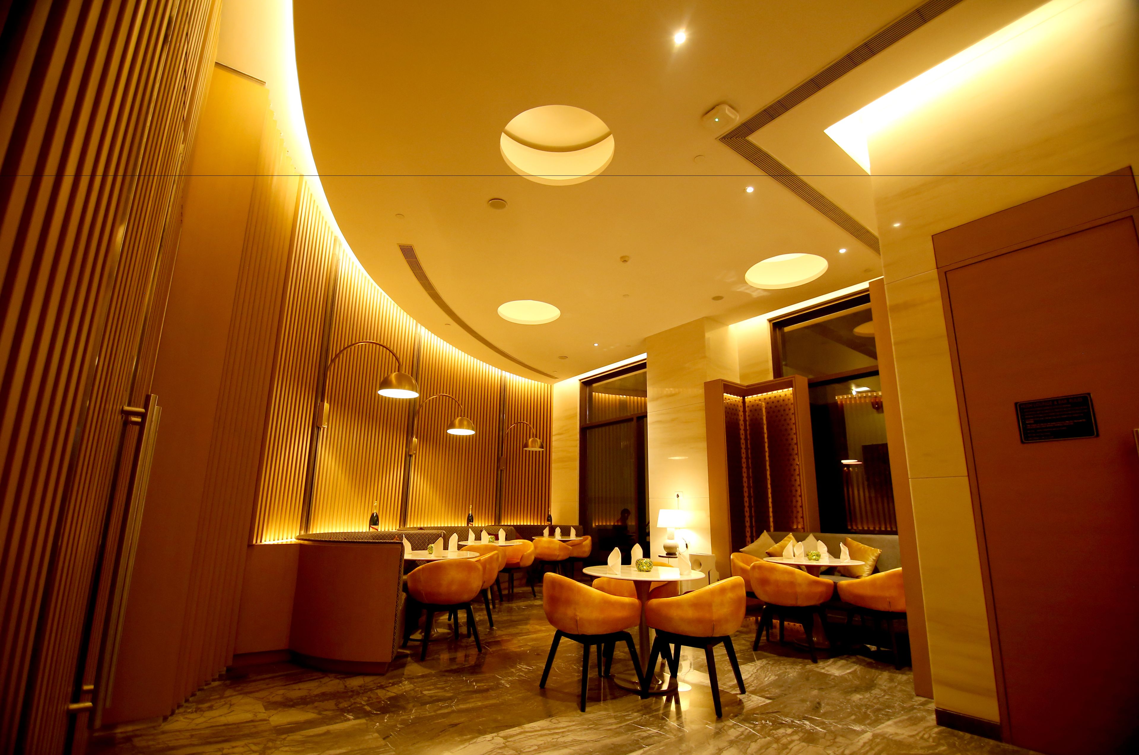 A modern hotel lobby with a curved ceiling, recessed lighting, and a marble floor.