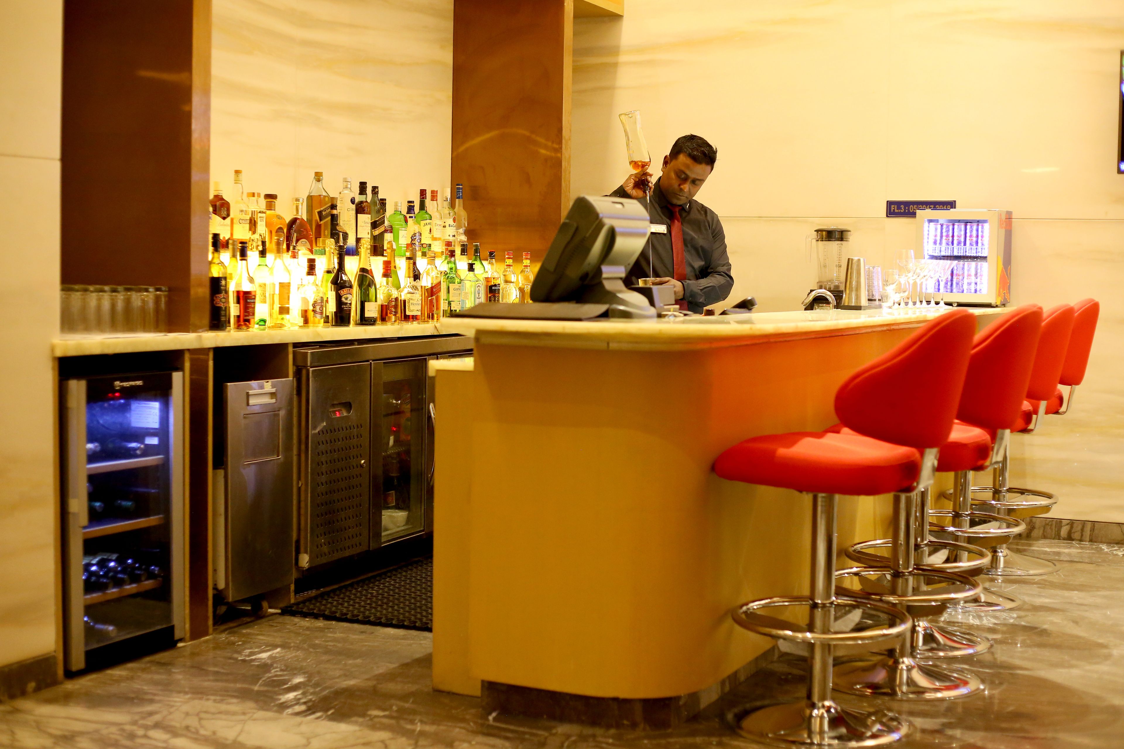 A bar area with a bartender, a variety of liquor bottles, and a modern bar counter.