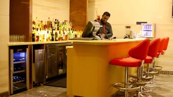 A bar area with a bartender, a variety of liquor bottles, and a modern bar counter.