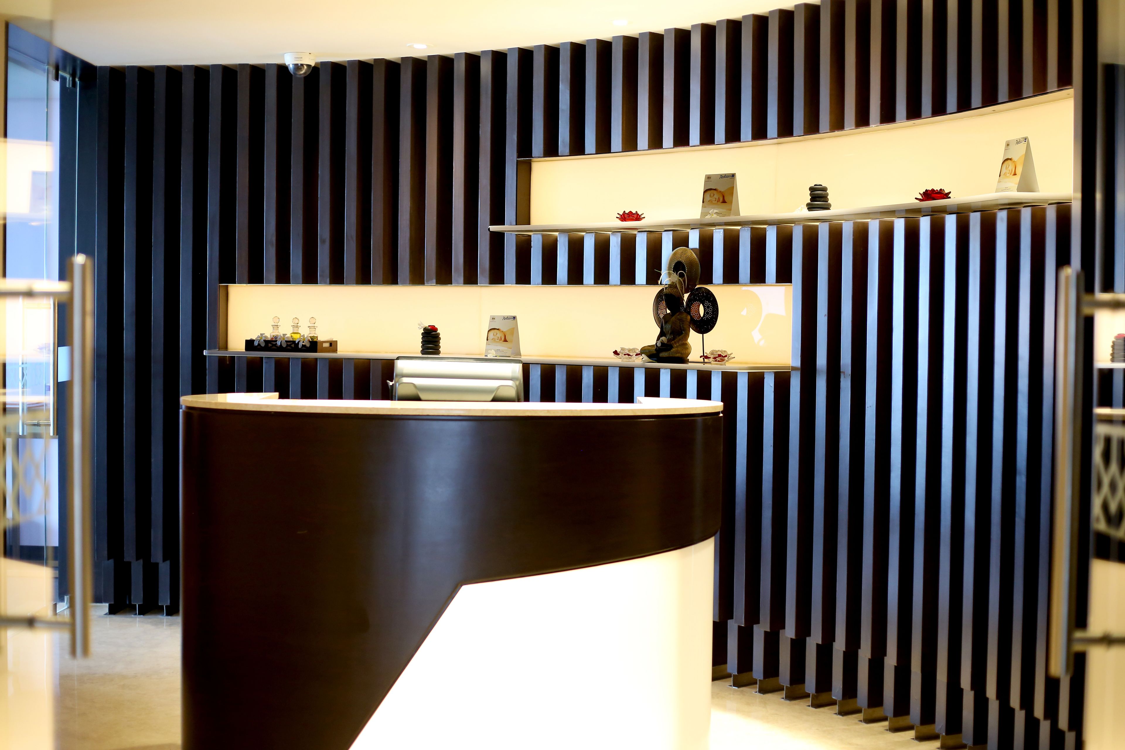 A modern reception desk with a curved design, flanked by vertical striped panels.