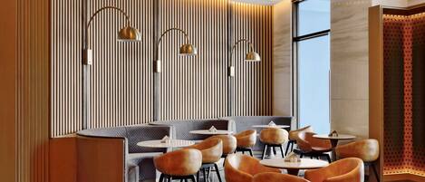 A modern dining area with a curved bench, round tables, and orange chairs.